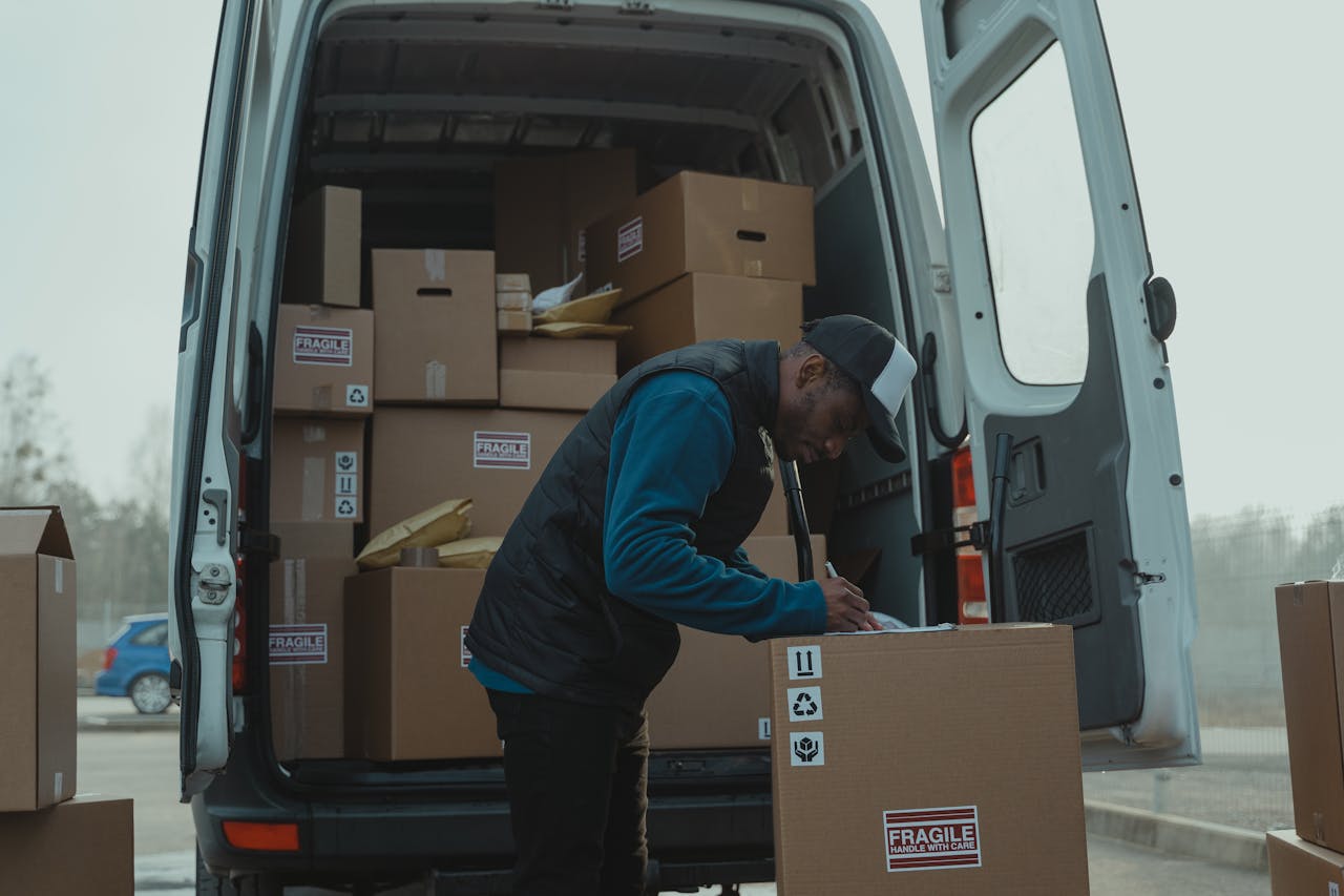 services-img Delivery man sorting packages in van, organizing shipments for distribution.